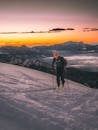 Skier climbs a snowy mountain with breathtaking sunset views, perfect for adventure enthusiasts.